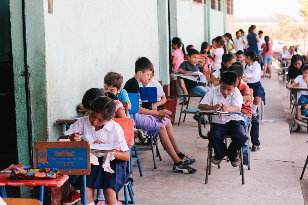 Guatemalan children sit outside at school desks