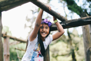 A girl in Guatemala hangs on a playground, smiling