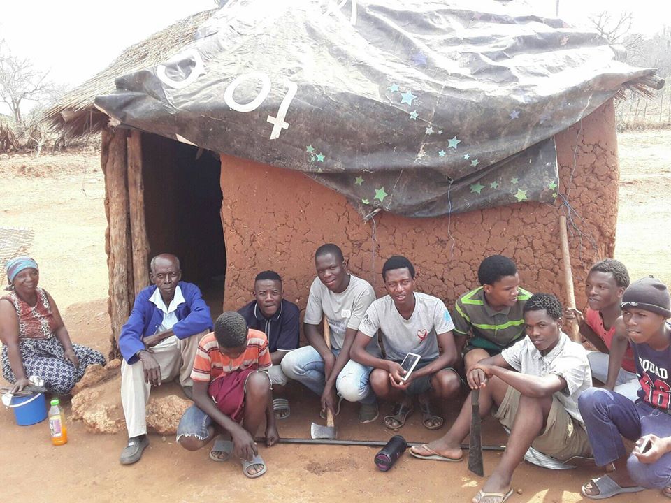 youth sitting outside of an elderly person's home in Eswatini