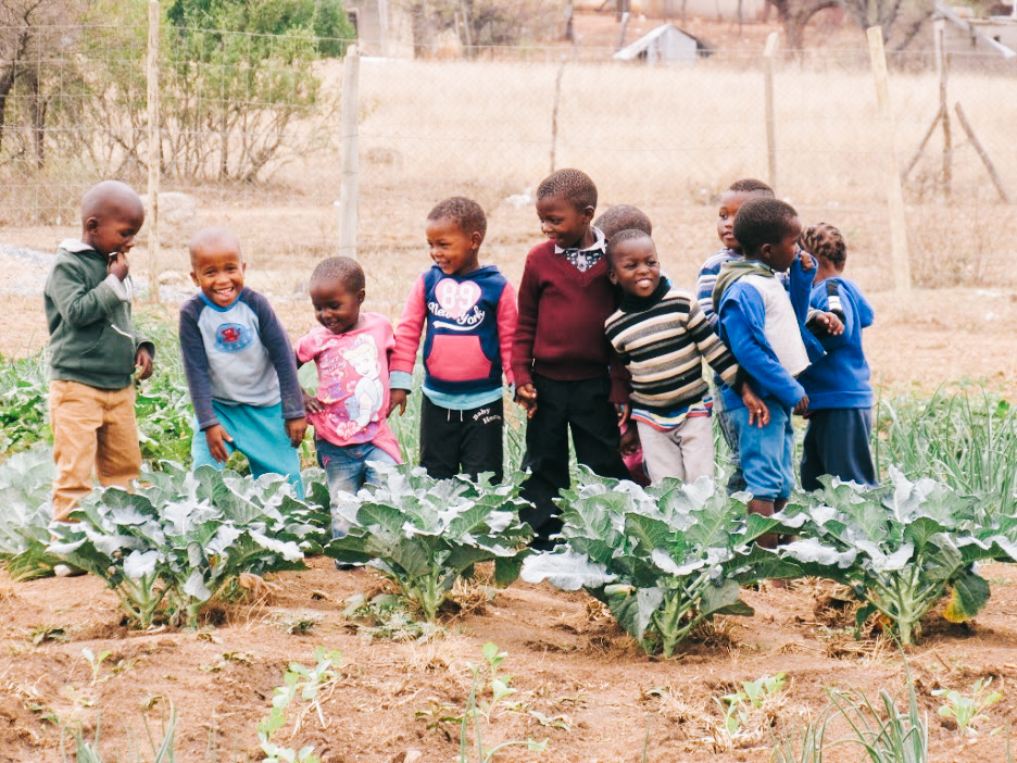 Children in Eswatini stand in their community garden