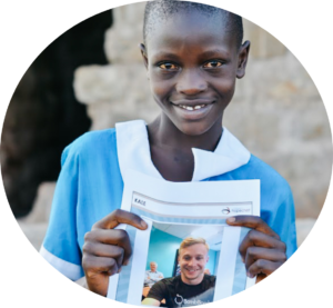 Young girl in Kenya holding a photo of her HopeChest Friend