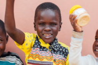 Three Ugandan children holding peanut butter