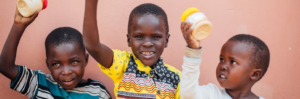 Three Ugandan children holding peanut butter