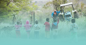 Young children watching a man doing agricultural work