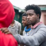 Ethiopian leader with his hand on the shoulder of someone in a red hoodie