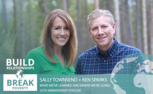 Photo of Sally and Ken standing next to each other smiling, holding a laptop.