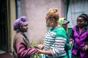 Ayni holding a woman's hands and smiling