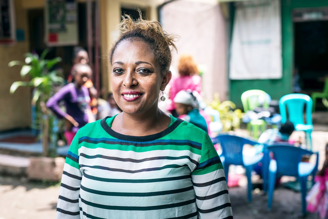 A woman in Ethiopia stands in front of a psychological support group.