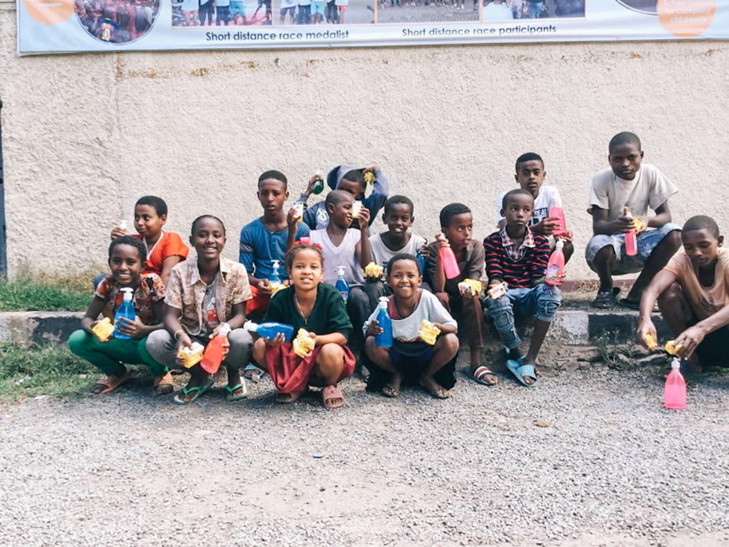 A group of children sits together holding soap