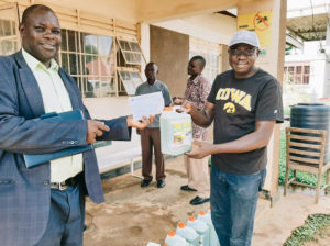 Simon and a government official in Uganda holding liquid soap