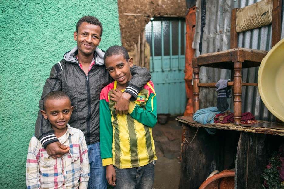 A dad in Ethiopia with his arms around his two young sons