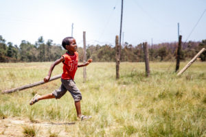 boy in Eswatini running through a fence