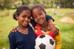 Two girls hugging with soccer ball