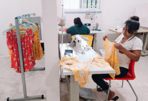 A woman sits at a sewing machine