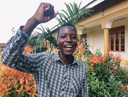 young man in Uganda with his hand raised in victory
