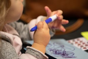 A child holds a blue marker in a close up shot