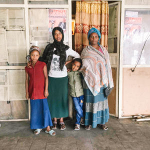 Shegitu's family standing in front of a building in Ethiopia