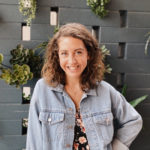 Portrait of Mariana in front of a wall of succulents