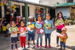A group of Guatemalan children hold up colorful paper hearts with pictures of their HopeChest Friends on them.